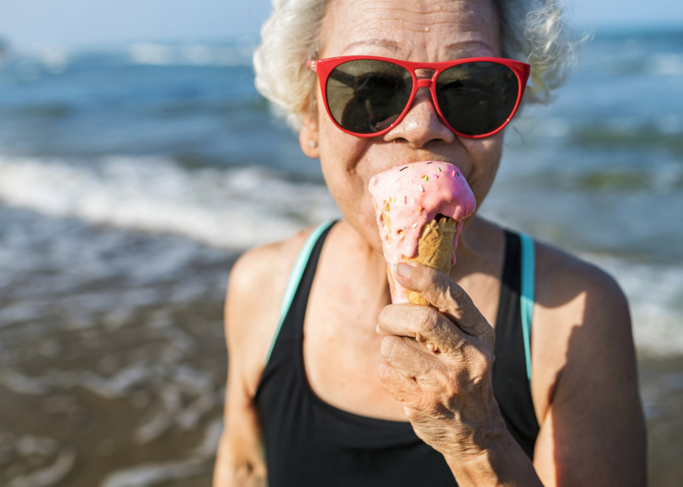 retired woman enjoying an ice cream cone at the beach